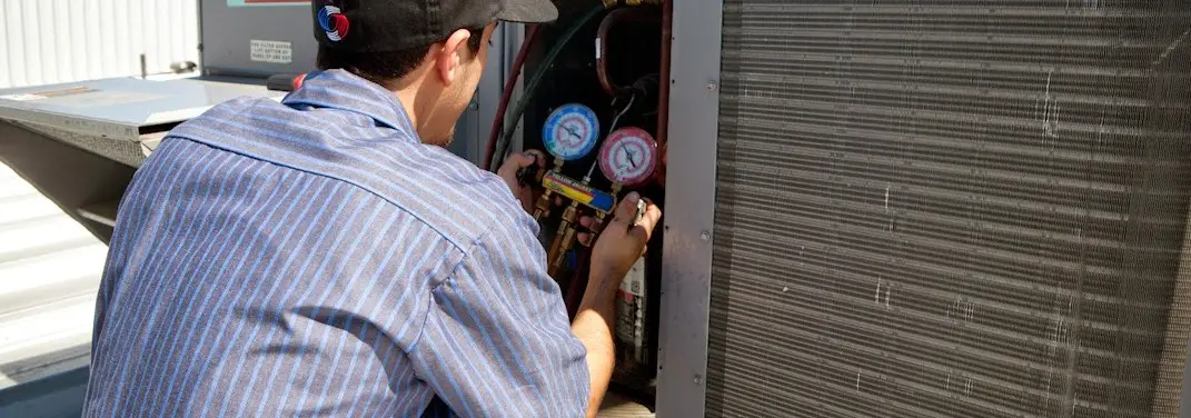 HVAC technician servicing a condenser unit in Tulare