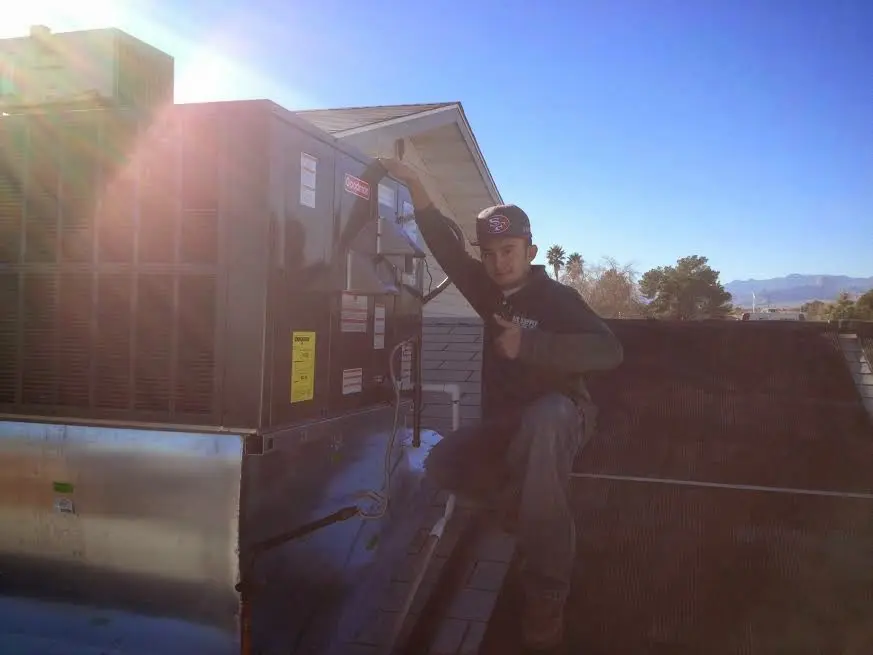 HVAC technician performing AC Tune-Up on a rooftop unit in Tulare